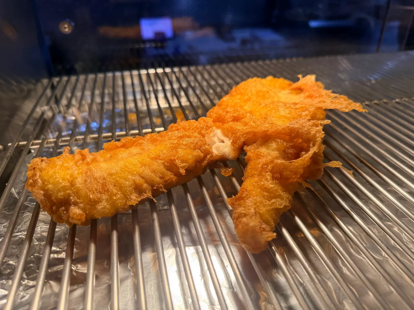 Freshly fried battered fish resting on the rack