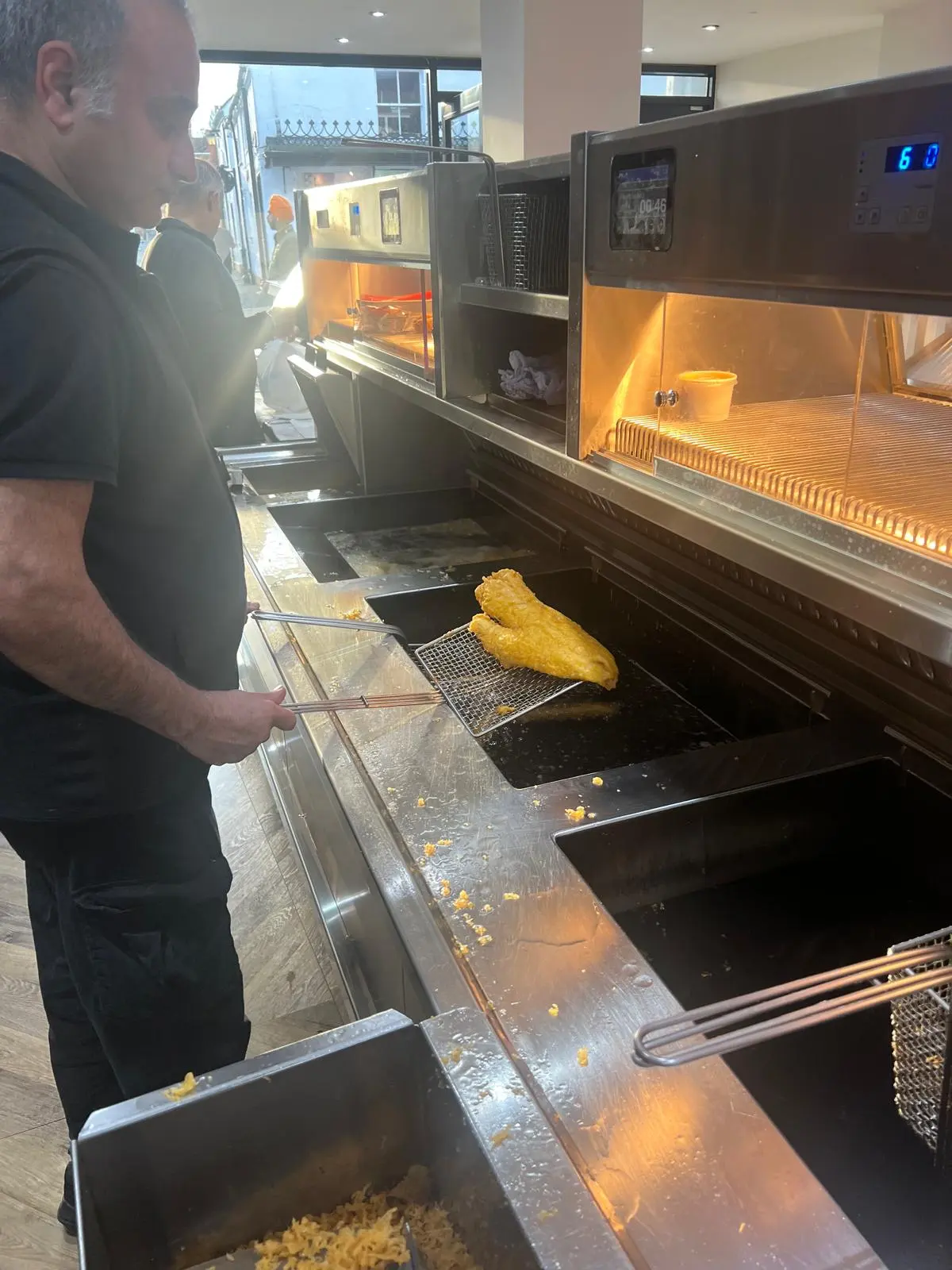 Tony lifting freshly battered fish out of the fryer